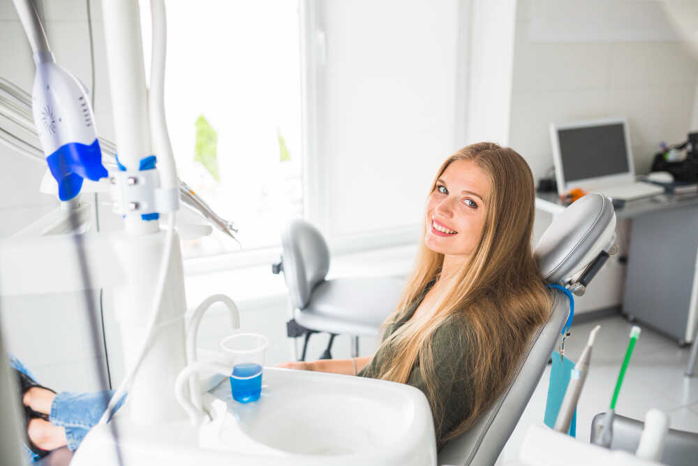 Młoda kobieta na fotelu ortodontycznym podczas wizyty kontrolnej Invisalign