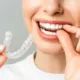 Młoda kobieta zdejmuje jedną nakładkę Invisalign i zakłada nową